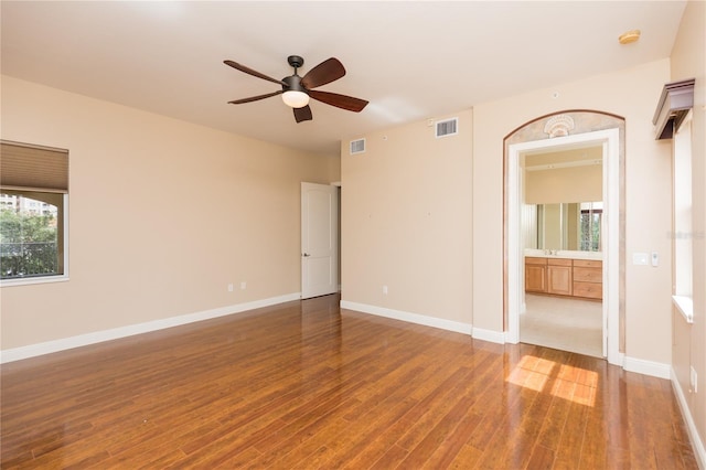 unfurnished bedroom with connected bathroom, wood finished floors, visible vents, and baseboards