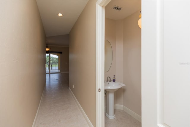 hall with light tile patterned floors, visible vents, baseboards, and a sink