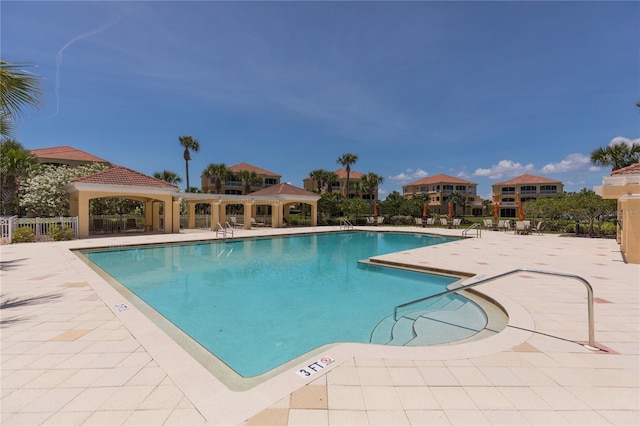 community pool with a gazebo, fence, and a patio