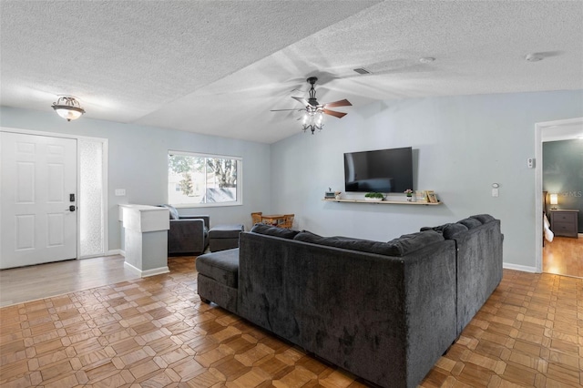 living area featuring lofted ceiling, a ceiling fan, baseboards, and a textured ceiling