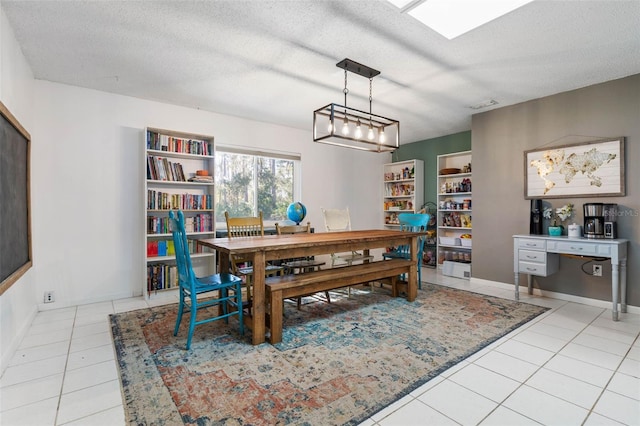 dining room featuring light tile patterned flooring, visible vents, a textured ceiling, and baseboards