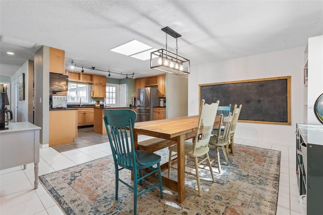 dining area with light tile patterned floors, rail lighting, and a textured ceiling