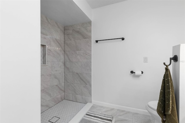 full bath featuring baseboards, tiled shower, toilet, and marble finish floor