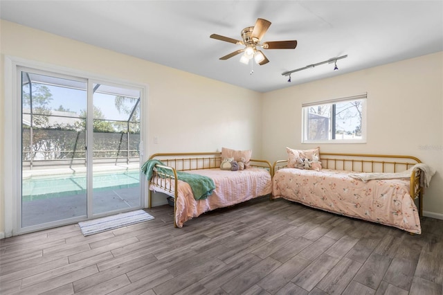 bedroom featuring ceiling fan, wood finished floors, access to exterior, and track lighting