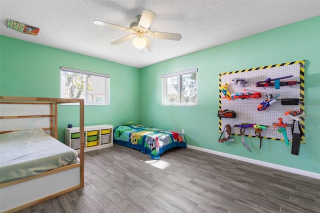 bedroom featuring a textured ceiling, a ceiling fan, baseboards, and wood finished floors