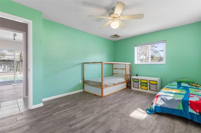 bedroom with baseboards, multiple windows, a textured ceiling, and wood finished floors