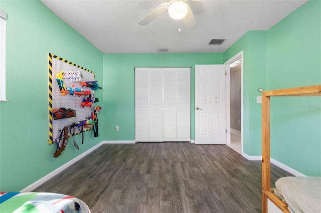 bedroom with a closet, visible vents, dark wood-type flooring, and baseboards