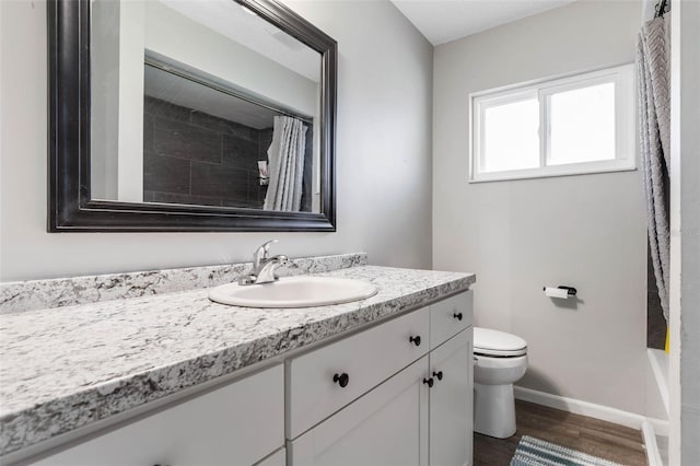 full bath featuring baseboards, toilet, wood finished floors, and vanity