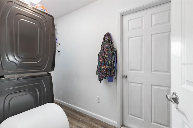 bathroom featuring stacked washer / drying machine, baseboards, and wood finished floors