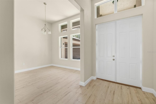 foyer featuring light wood-style floors, baseboards, and a chandelier