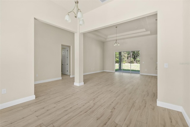 unfurnished room with a tray ceiling, baseboards, and light wood finished floors