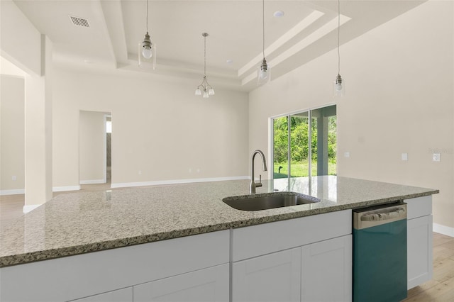 kitchen featuring a sink, dishwashing machine, visible vents, and a tray ceiling