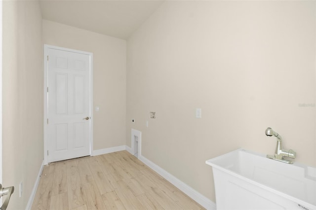 washroom featuring electric dryer hookup, light wood-style flooring, a sink, baseboards, and laundry area