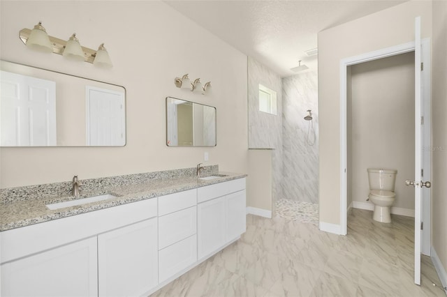 full bath featuring toilet, marble finish floor, a sink, double vanity, and walk in shower