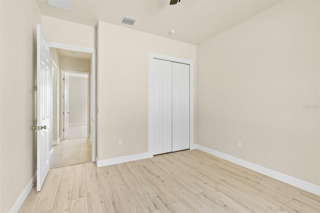 unfurnished bedroom with a closet, visible vents, light wood-style flooring, and baseboards