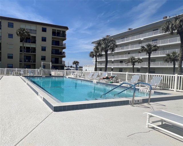 community pool with a patio and fence