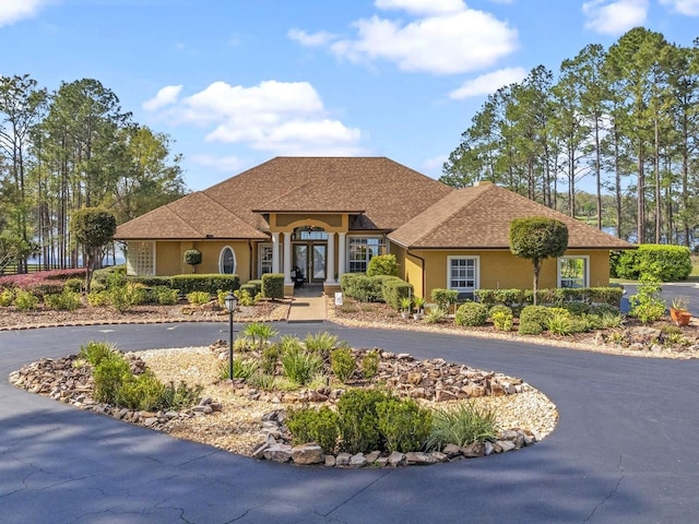 view of front of house with stucco siding and curved driveway