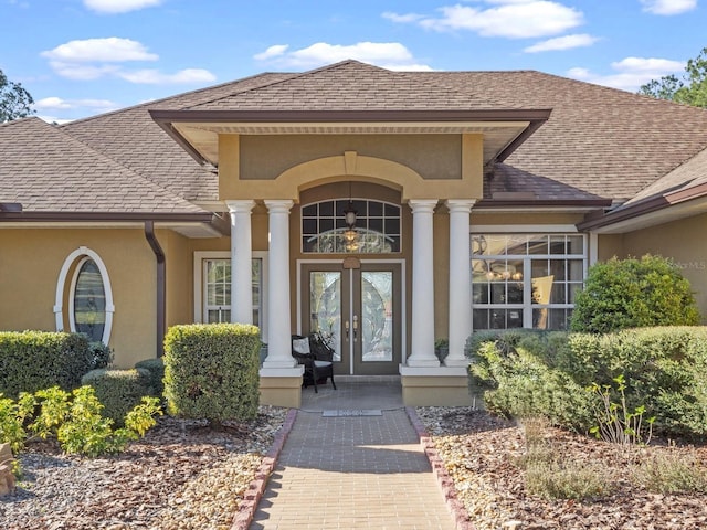 property entrance with stucco siding, french doors, and a shingled roof