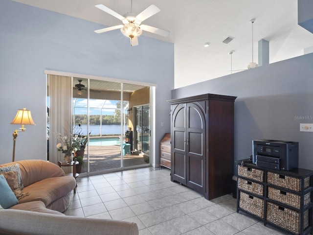 living room featuring visible vents, a water view, light tile patterned floors, a high ceiling, and a ceiling fan