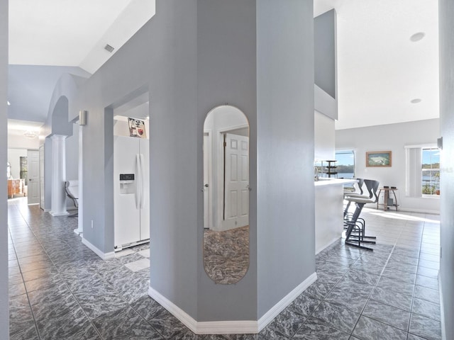 hallway featuring visible vents, baseboards, arched walkways, and high vaulted ceiling