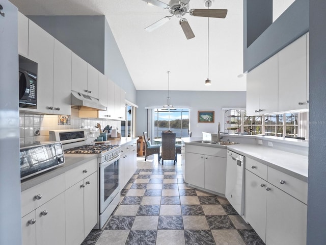 kitchen with black microwave, under cabinet range hood, range with gas stovetop, white dishwasher, and a sink