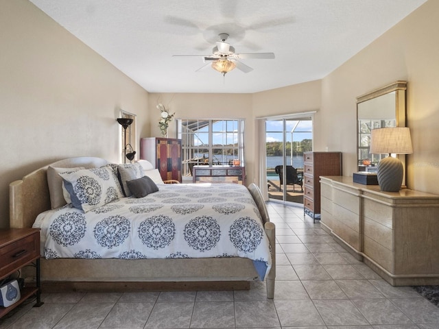 bedroom featuring access to exterior, a water view, ceiling fan, and light tile patterned flooring