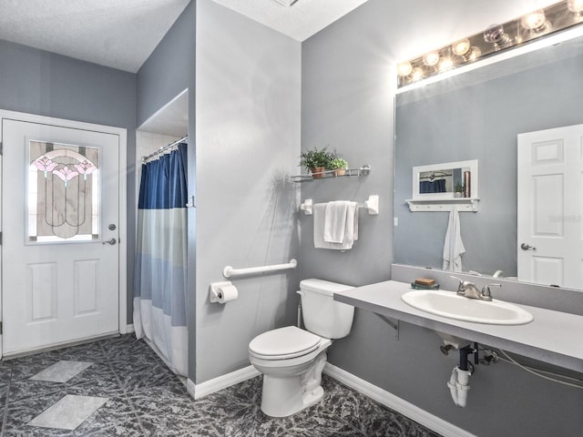 bathroom with a sink, curtained shower, baseboards, and toilet