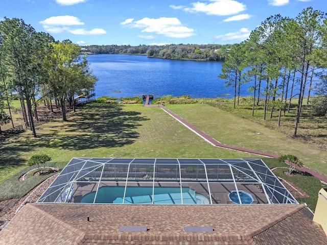 pool featuring glass enclosure, a patio area, a water view, and a lawn