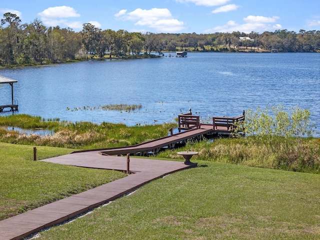 view of dock with a yard and a water view