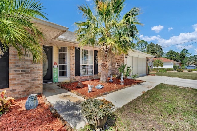 entrance to property featuring brick siding, driveway, and a yard