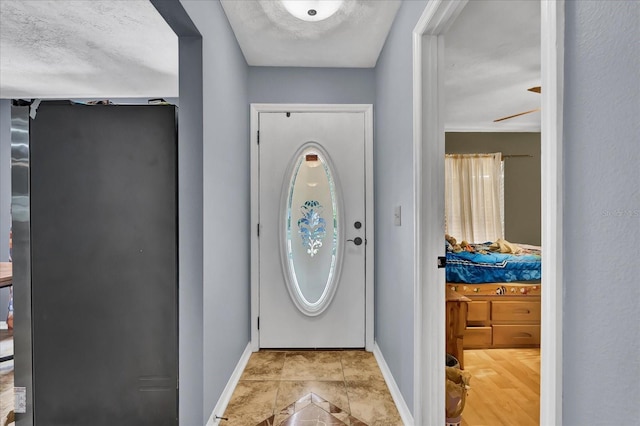 tiled foyer entrance featuring baseboards and a textured ceiling