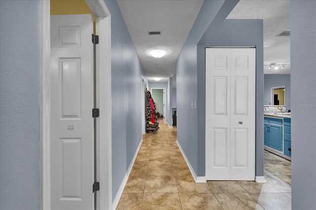 corridor with light tile patterned flooring, visible vents, and baseboards