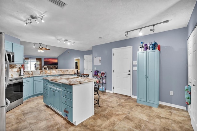 kitchen featuring blue cabinetry, a sink, a center island, stainless steel appliances, and a breakfast bar area