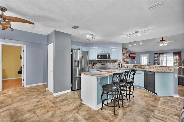 kitchen with a breakfast bar area, visible vents, a peninsula, ceiling fan, and appliances with stainless steel finishes