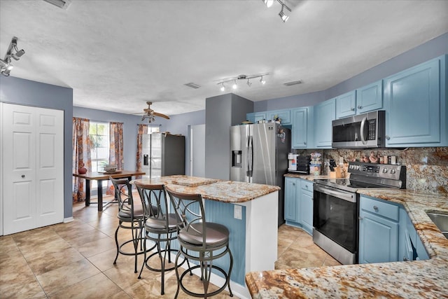 kitchen with tasteful backsplash, blue cabinetry, appliances with stainless steel finishes, and a breakfast bar area