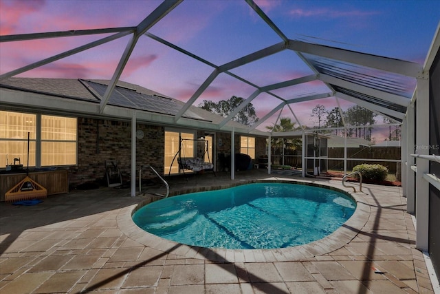 pool at dusk featuring a patio area, an outdoor pool, a lanai, and fence