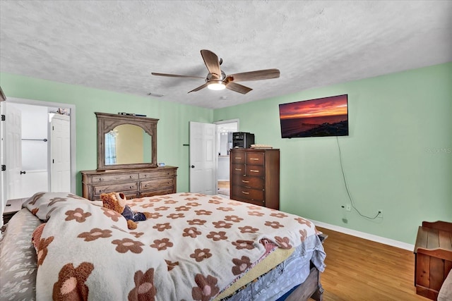 bedroom featuring ceiling fan, baseboards, a textured ceiling, and wood finished floors