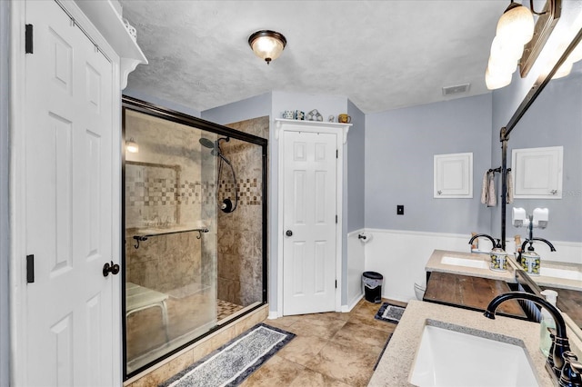 full bath featuring a shower stall, double vanity, visible vents, and a sink