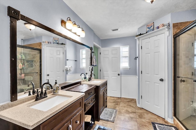 bathroom featuring tile patterned flooring, visible vents, a stall shower, and vanity