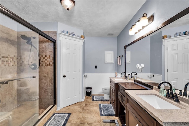 full bathroom featuring vanity, toilet, visible vents, and a stall shower