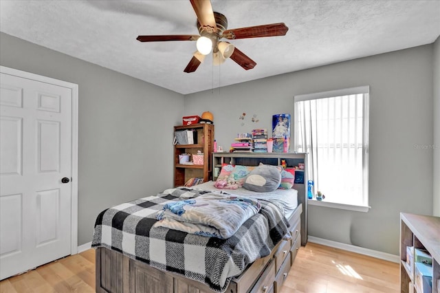 bedroom with light wood-style floors, baseboards, and a textured ceiling