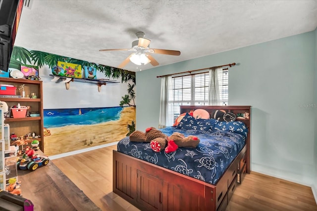 bedroom with ceiling fan, baseboards, a textured ceiling, and wood finished floors