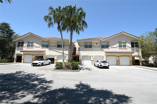 view of front of property featuring stucco siding, an attached garage, a tile roof, and driveway