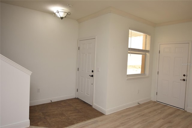 foyer with crown molding, baseboards, and wood finished floors