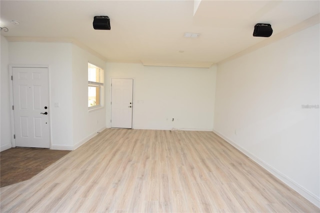 spare room featuring baseboards, light wood-style floors, and ornamental molding