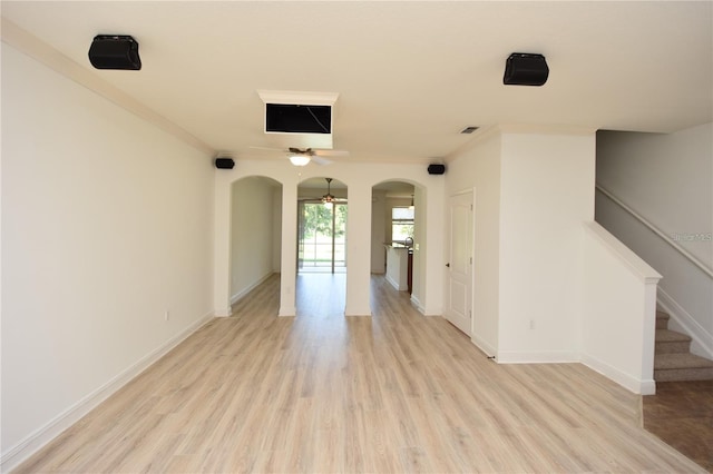 unfurnished room featuring ceiling fan, arched walkways, ornamental molding, and light wood finished floors