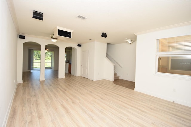 unfurnished room featuring stairway, a ceiling fan, visible vents, light wood-style flooring, and arched walkways