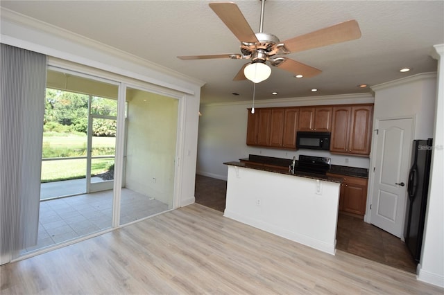 kitchen with dark countertops, light wood finished floors, black appliances, and crown molding