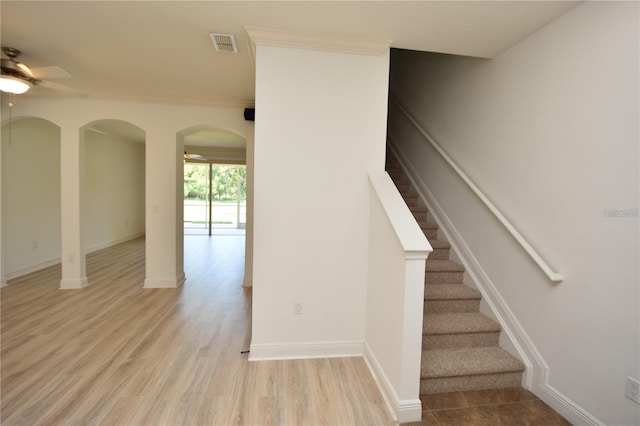 stairs featuring wood finished floors, a ceiling fan, visible vents, and baseboards