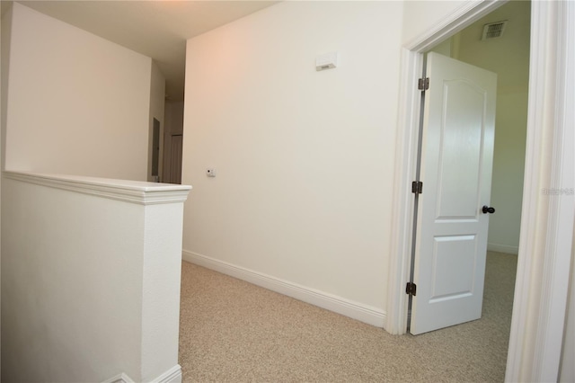 corridor featuring visible vents, baseboards, and light colored carpet